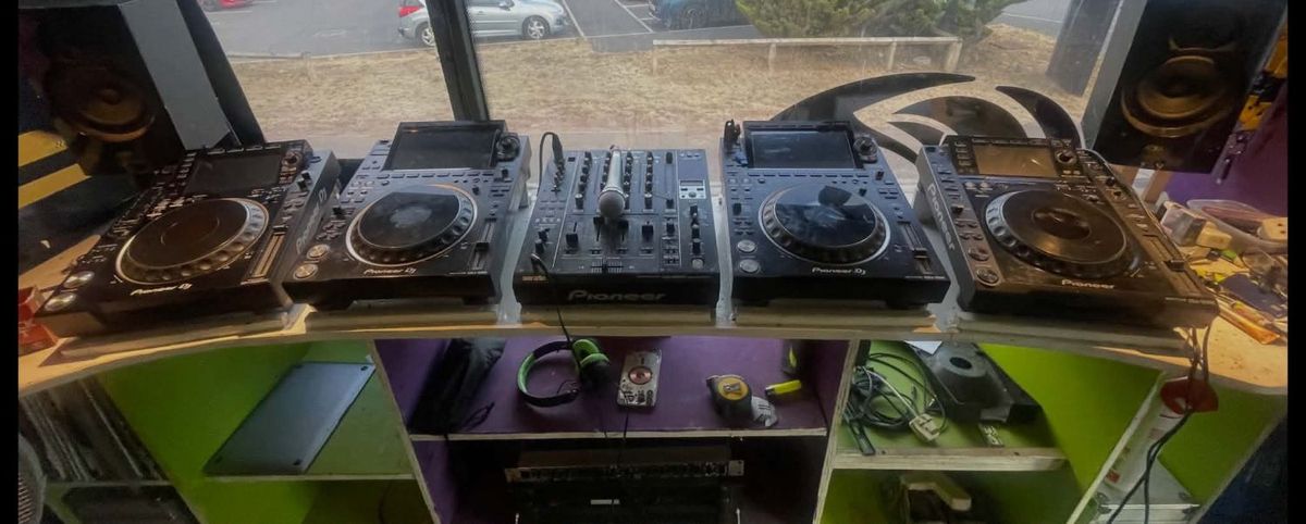 Four Pioneer CDJ decks and a Pioneer mixer built into the lime and purple booth inside the bus, with monitor speakers either side