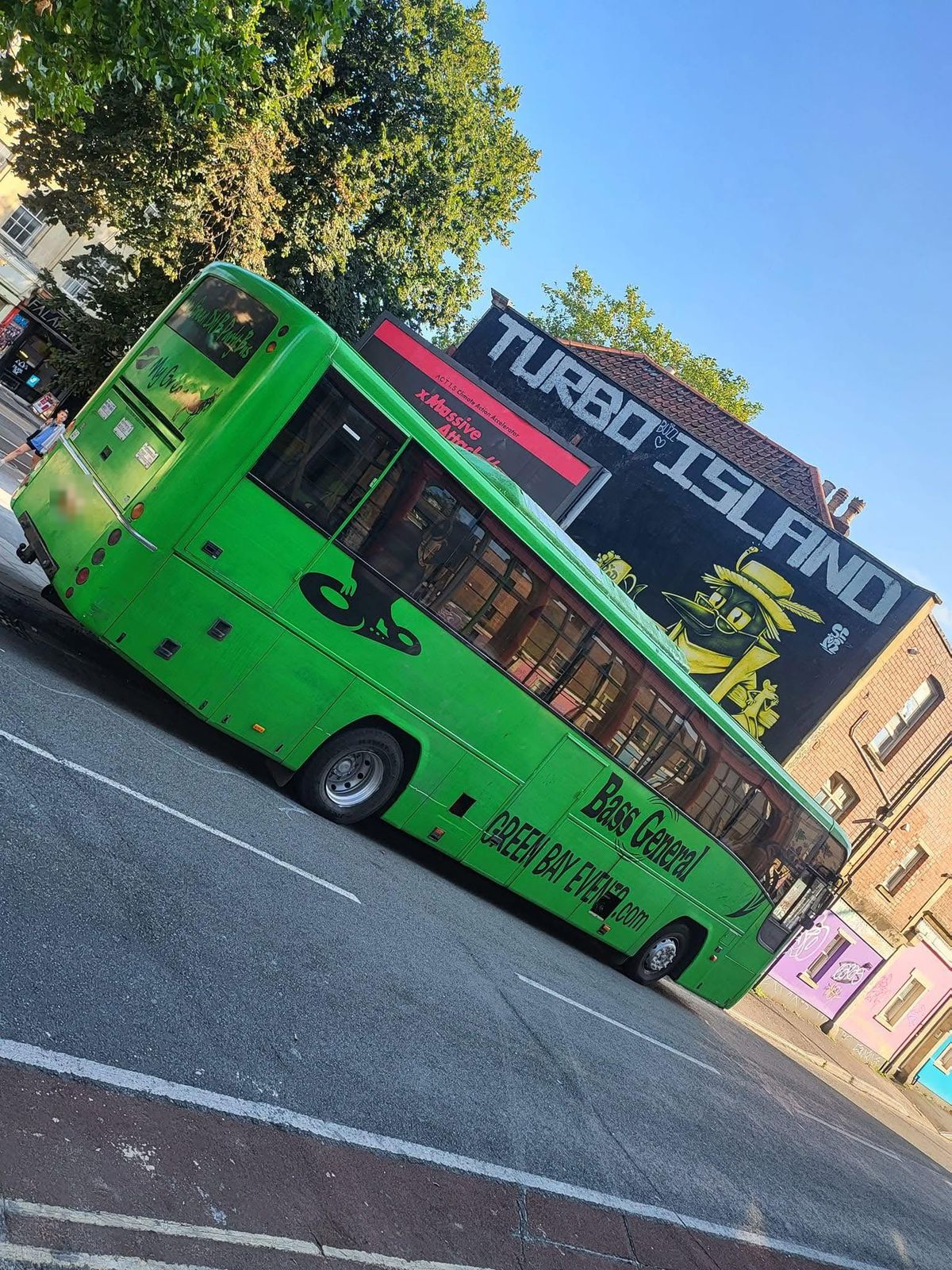 The lime-green party bus parked under the Turbo Island mural in Bristol
